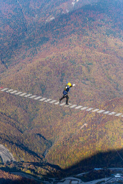 Adventurer crosses suspension bridge over snowy abyss 