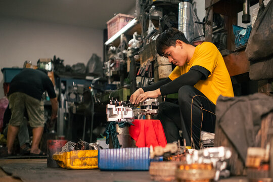 Automotive mechanic skillfully repairing engine alternator in garage