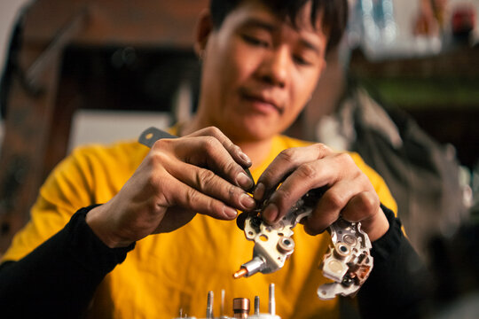 Mechanic hands assembling engine starter during car repair maintanence