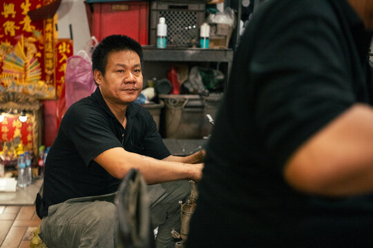 Asian mechanic resting in workshop while focusing on a task