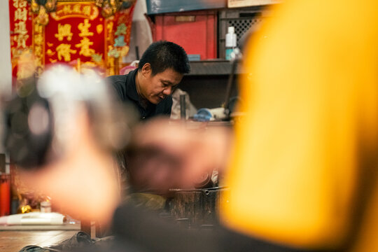 Asian mechanic concentrating on engine repair in traditional workshop