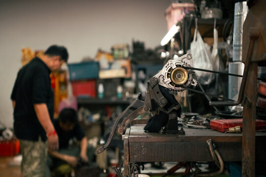 Alternator unit with belt in focus at automotive workshop