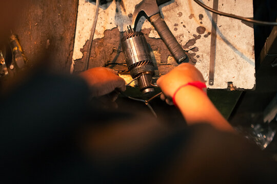 Mechanic repairing component on workbench hands wiring motor part