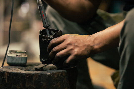 Hand working on motor part with tool in industrial workshop
