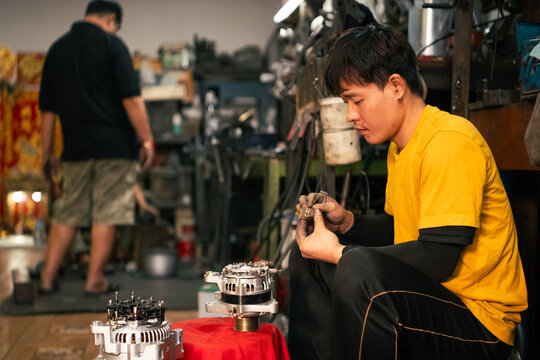 Mechanic hand assembling engine parts in workshop providing