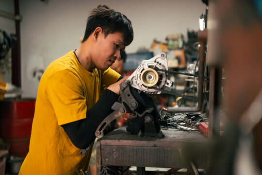 Mechanic repairing vehicle alternator, providing professional