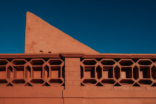 Terracotta wall with geometric fence under blue sky