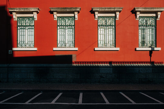 Red facade with decorative windows and strong shadows