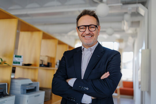 Experienced professional smiling standing with crossed arms at office