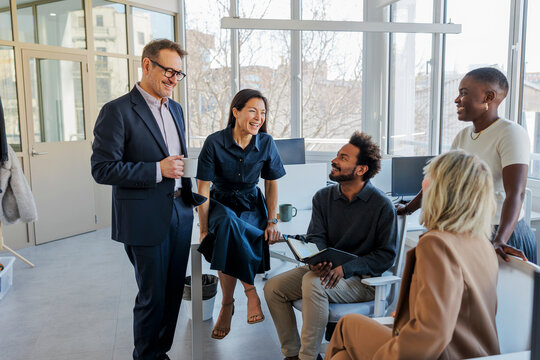 Business team collaborating and laughing in modern office