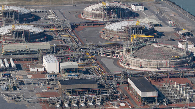 Aerial view of Fluxys - LNG Terminal Zeebrugge with large domed storage tanks, intricate industrial piping, and support buildings in Brugge, Vlaanderen, Belgium.