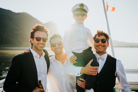 Groom and friends with child enjoying playful moment during lake