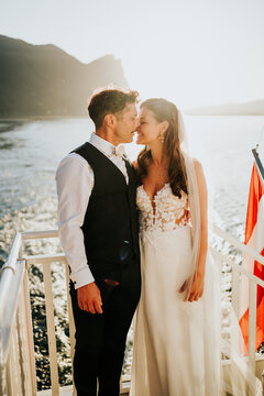 Bride and groom sharing intimate moment on boat at sunset on Mon