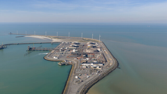 Aerial view of the Fluxys LNG Terminal Zeebrugge featuring storage tanks and wind turbines along the coastline in Brugge, Vlaanderen, Belgium.