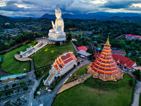 Aerial view of Wat Huay Pla Kang temple complex featuring the giant white Guan Yin statue and the nine-tier pagoda at twilight in Tambon Ban Du, Chang Wat Chiang Rai, Thailand.