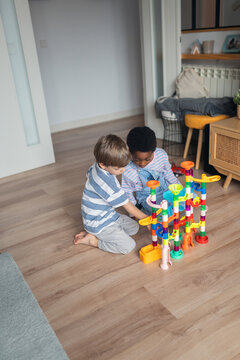 Children building marble run on living room floor