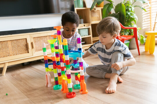 Children playing colorful marble run toy at home