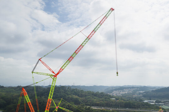Giant Colorful Construction Crane Overlooking Hills and Town