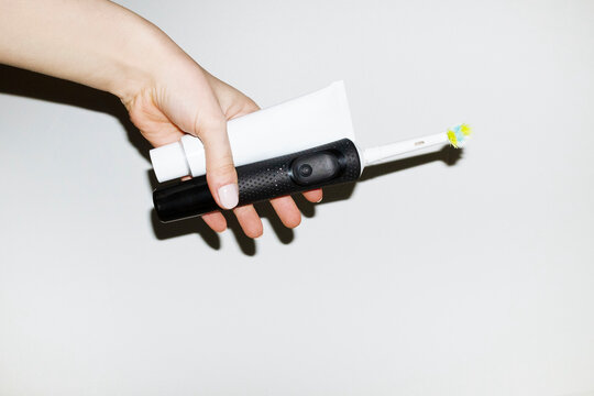 Hand holding electric toothbrush and toothpaste with flashlight