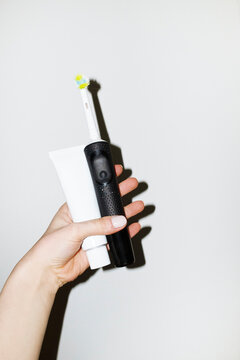Hand holding electric toothbrush and toothpaste with flashlight