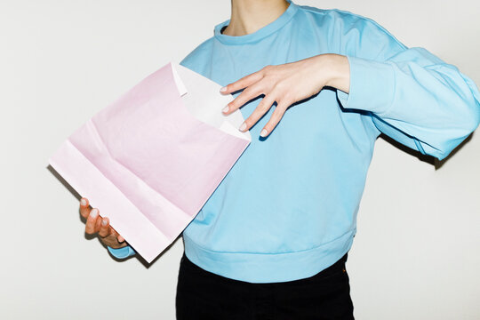 Person holding pastel pink mockup paper bag with empty space for text 