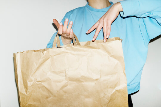 Person holding pastel brown mockup paper bag and empty space for text 