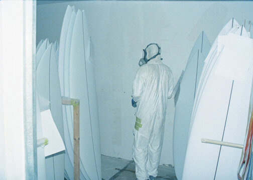 Surfboard craftsman wearing protective clothing checking board orders
