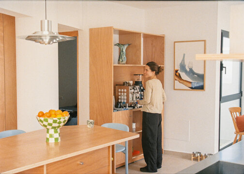 Woman making coffee in the living room of her home with soft light