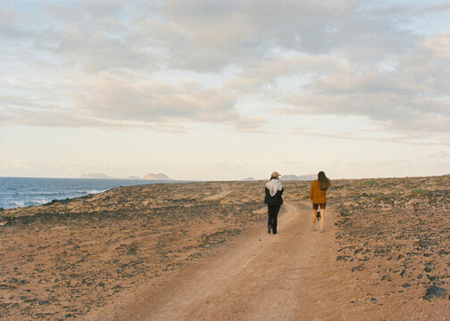 Analog shot of friends walking along a rocky trail in sunlit landscape
