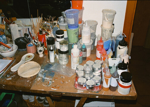 A cluttered shelf filled with painting and crafting supplies