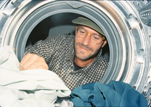 Film-style interior perspective from a dryer of man collecting laundry