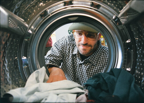 Analog shot from inside a dryer of a man taking out clean clothes