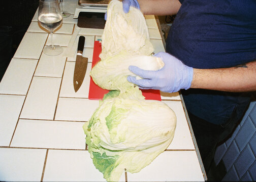 Anonymous man chopping cabbage on a kitchen while preparing kimchi