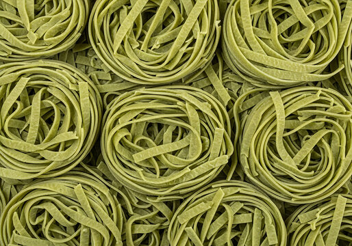 Freshly prepared green pasta bundles neatly.