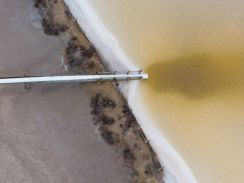Salt water flowing from a supply pipe into a colorful settling pond 