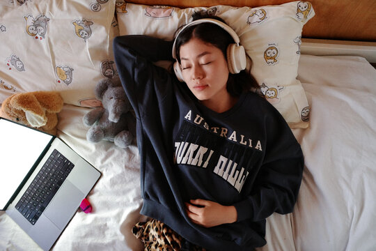 Person sleeping with headphones on bed after studying