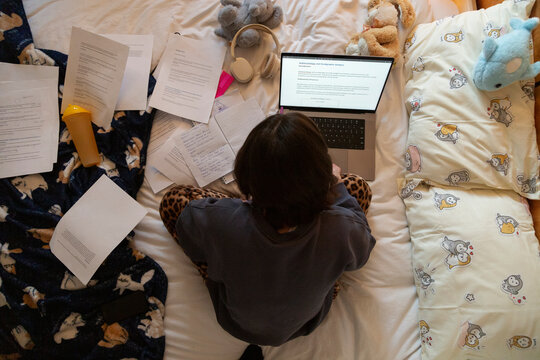 Student cross-legged studying for exams on bed