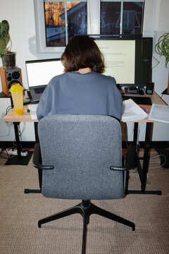 Student studying on laptop and computer monitors at home