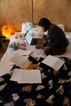 Person studying diligently for exams in bed