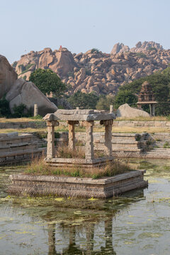 Stone pavilion in lotus pond with granite hills in Hampi, India