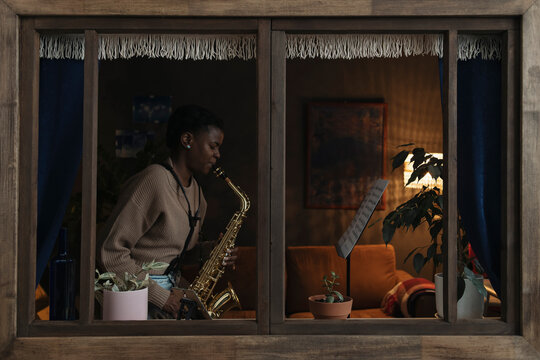 Woman playing saxophone from sheet music at home