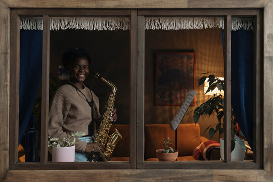 Woman playing saxophone from sheet music at home