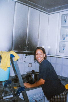 Young woman cleaning a burnt kitchen with optimism