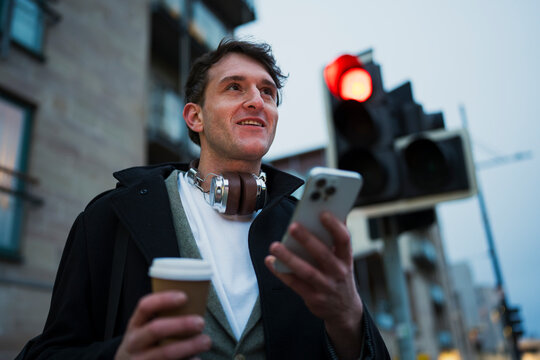Man with coffee waits at crosswalk
