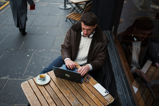 Man works on laptop at cafe table
