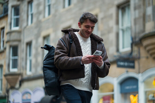 Man walks while using phone in city

