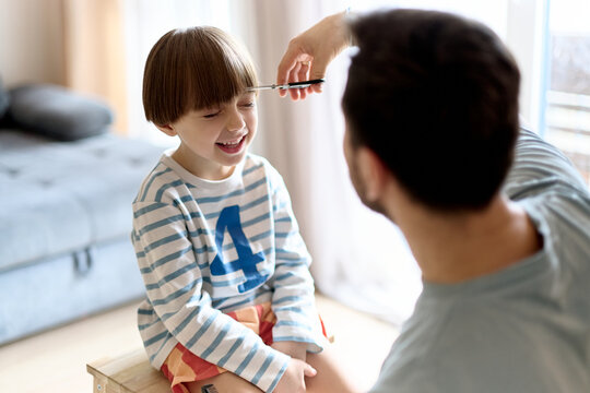 Father trimming son&rsquo;s bangs at home