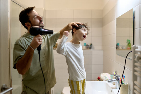Father drying little boy&rsquo;s hair in bathroom