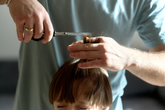 Father cutting son&rsquo;s hair at home from above
