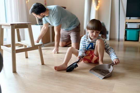 Father and son cleaning floor after haircut